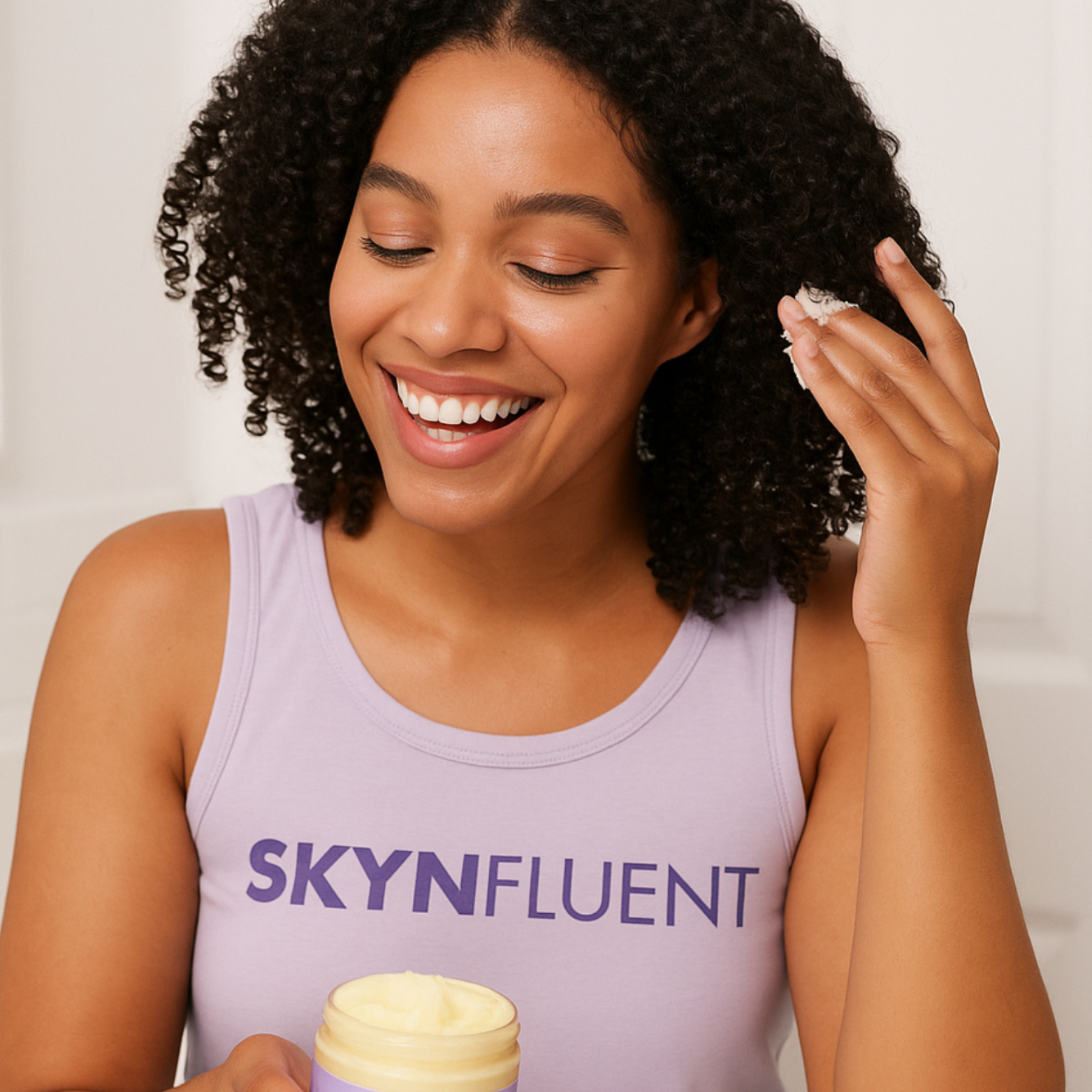 Smiling woman with curly hair applying Chebe Hair Repair Butter to her curls.
